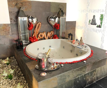 Foto del jacuzzi decorado con globos y champán, en la habitación del apartamento deluxe de Alaia Holidays Gran Vía