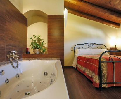 Dormitorio con bañera de hidromasaje privada junto a la cama del apartamento dúplex de este establecimiento.