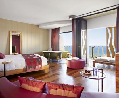 Foto de una de las Suites Junior esquineras con bañera cerca de la cama y terraza con vistas al mar.