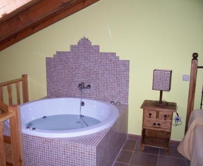 Foto de la bañera de hidromasajes junto a la cama de una de las casas rurales.