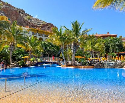 Hermosa piscina exterior de tipo laguna rodeada de vegetación de este hotel.