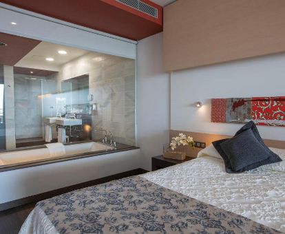 Suite deluxe con vistas al mar y bañera de hidromasaje privada junto a la cama de este moderno hotel.