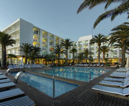 Amplia zona exterior con piscinas y tumbonas rodeada de palmeras de este hotel solo para adultos.