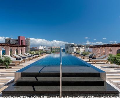 Terraza solarium con piscina al aire libre y vistas a la ciudad de este lujoso hotel.