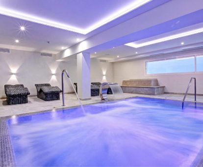 Amplia piscina con elementos de hidroterapia y zona de relajación del centro de bienestar del hotel.