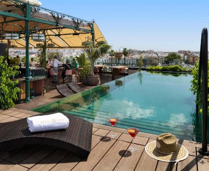 Terraza con vistas a la ciudad, piscina al aire libre y mobiliario en este hotel solo para adultos.
