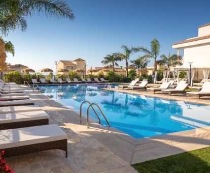 Amplia zona exterior con piscina rodeada de tumbonas de este romántico hotel.