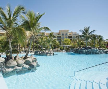 Foto de una de las amplias piscinas al aire libre con tumbonas y un entorno tropical.