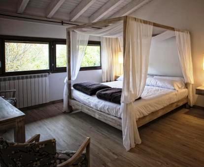 Foto de una de las habitaciones con cama con dosel y vistas al jardín.