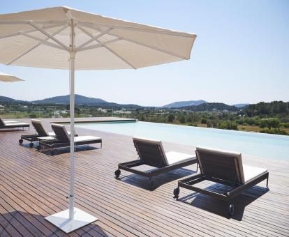 Terraza con piscina de borde infinito, solarium y vistas al paisaje que rodea este hotel solo para adultos.