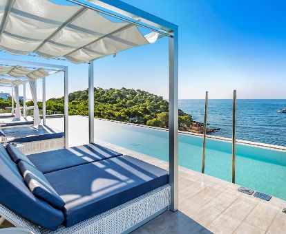 Solarium con tumbonas y piscina al aire libre con vistas al mar en este maravilloso hotel solo para adultos.