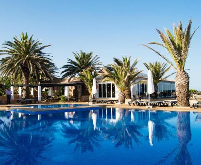 Exterior de este alojamiento ideal para parejas con piscina al aire libre rodeada de palmeras.