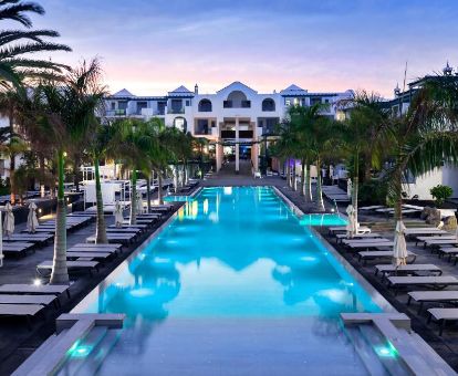 Zona exterior con piscina, solarium y palmeras de este fabuloso hotel solo para adultos.