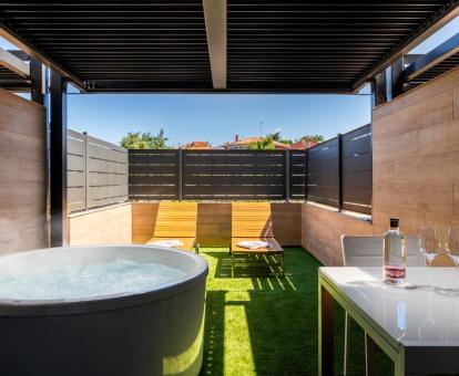 Terraza amueblada con una amplia bañera de hidromasaje privada exterior de la habitación doble deluxe del hotel.