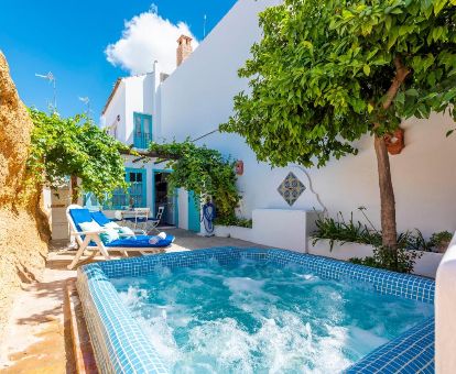 Terraza con mobiliario y jacuzzi privado en el exterior de una de las casas de este complejo rural.