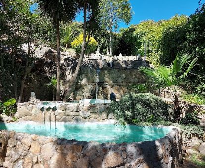 Hermosa piscina con chorros en cascada rodeada de vegetación de este hotel rural.