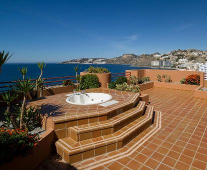 Gran terraza privada con jacuzzi al aire libre de la suite con vistas al mar del hotel.