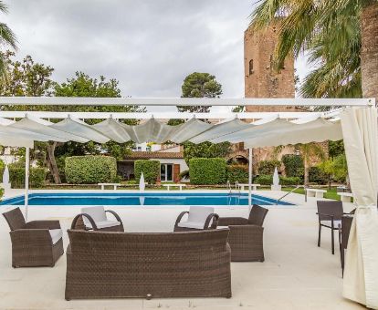 Amplio espacio exterior con piscina y mobiliario de este hotel, rodeado de vegetación.