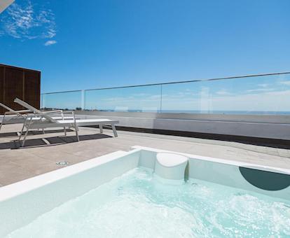 Terraza con bañera de hidromasaje privada y vistas al mar del apartamento superior de este establecimiento.