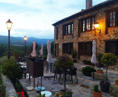 Edificio de piedra de este hotel rural con terraza amueblada y vistas al paisaje.