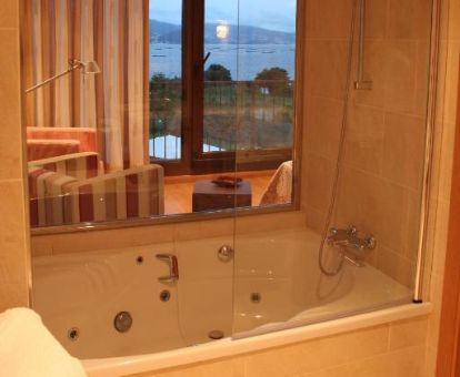 Bañera de hidromasaje privada con vistas al exterior en la suite de este acogedor hotel.