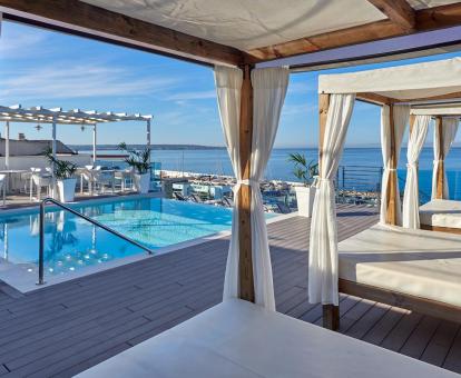 Foto de la piscina del hotel con vistas al mar y camas balinesas.
