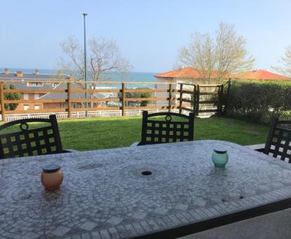 Foto de la zona ajardinada con vistas al mar y mobiliario exterior del apartamento.