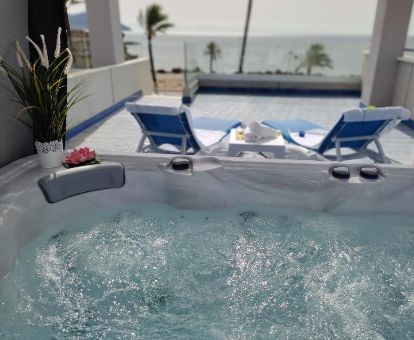 Terraza con un gran jacuzzi privado, tumbonas y vistas al mar del apartamento superior del complejo.