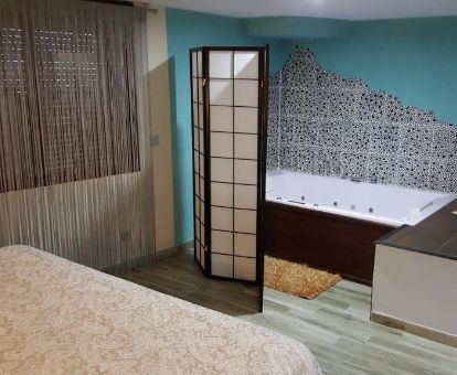 Dormitorio con bañera de hidromasaje privada junto a la cama de uno de los apartamentos del establecimiento.