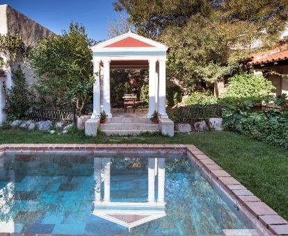 Acogedora zona exterior con piscina y bellos jardines de este hotel romántico con inspiración romana.