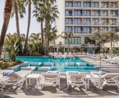 Amplia zona exterior con piscina y solarium rodeado de palmeras de este hotel romántico.