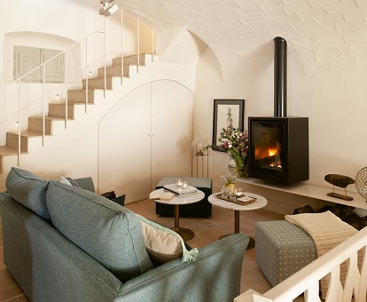 Foto del salón donde se ven los sofás y la chimenea encendida que contrasta con el color blanco de la decoración de paredes y muebles.