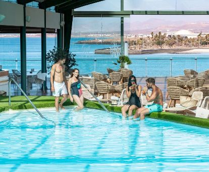 Parejas disfrutando de la piscina con vistas al mar y a la ciudad de este romántico hotel.