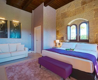 Una de las coquetas habitaciones de estilo tradicional con paredes de piedra a la vista y sala de estar de este hotel rural.