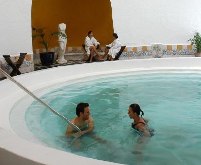 Varias personas disfrutan de la zona de aguas del centro de bienestar de este establecimiento ideal para parejas.