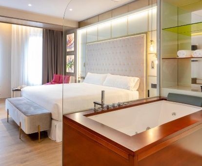 Una de las elegantes habitaciones con <strong>bañera de hidromasaje privada</strong> junto a la cama de este moderno hotel.