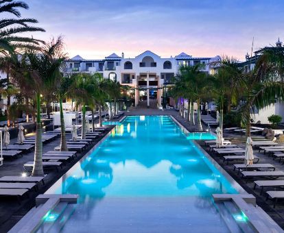 Maravillosa zona exterior con piscina y tumbonas rodeada de palmeras de este hotel solo para adultos.