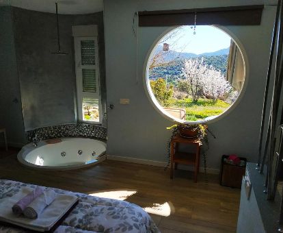 Dormitorio con jacuzzi privado cerca de la cama y hermosas vistas al jardín de esta casa independiente.