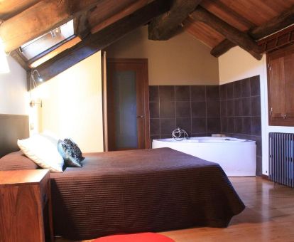 Coqueta habitación doble superior con bañera de hidromasaje privada junto a la cama en este hotel romántico.