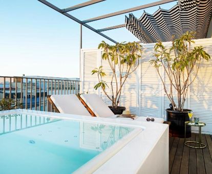 Hermosa terraza con tumbonas y jacuzzi privado del ático de este moderno hotel.