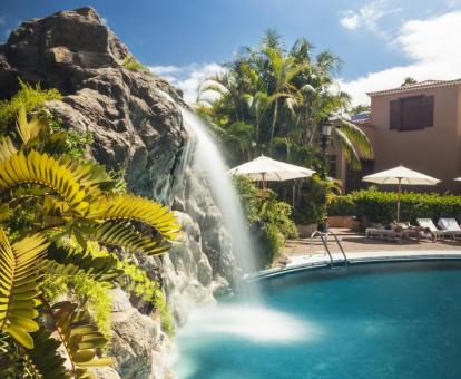 Foto de la piscina del hotel con cascada y entorno natural.