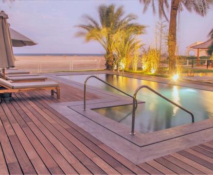Foto de la piscina con cómodas tumbonas junto a la playa.