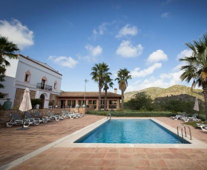 Hotel rural rodeado de vegetación con piscina al aire libre.