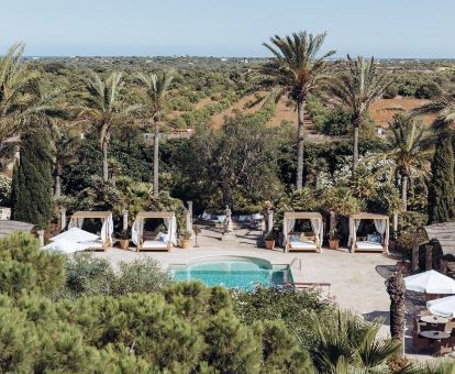 Agradable zona exterior rodeada de vegetación con piscina y solarium con camas balinesas de este hermoso hotel ideal para descansar en pareja.