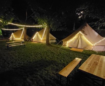 Acogedoras tiendas con iluminación nocturna y zona exterior de este camping en la naturaleza.
