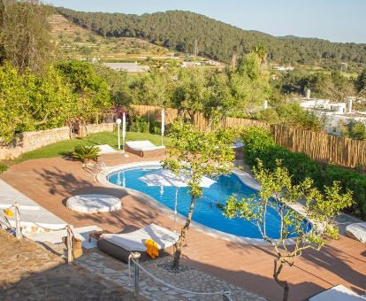 Amplio espacio exterior con piscina y mobiliario de este hotel solo para adultos rodeado de vegetación.