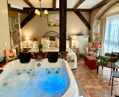Habitación con un gran jacuzzi privado cerca de la cama de este coqueto establecimiento ideal para parejas. 
