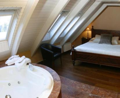 Acogedora suite con bañera de hidromasaje privada cerca de la cama.