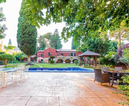 Edificio de este acogedor hotel rural con piscina rodeada de vegetación y terraza con mobiliario al aire libre.