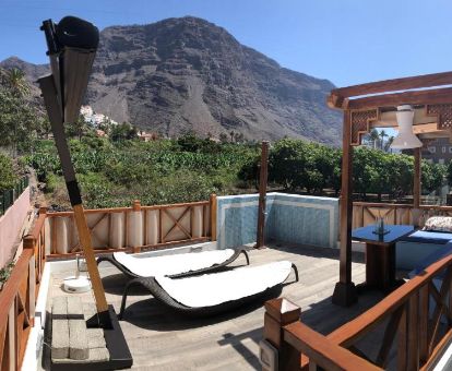 Hermosa terraza solarium con mobiliario y vistas a las montañas de uno de los apartamentos del complejo.